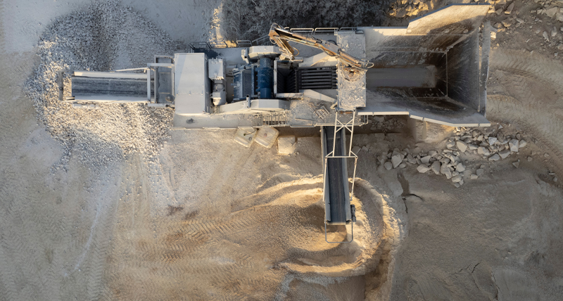 Aerial view of an industrial mining site with a large conveyor system and piles of extracted material, demonstrating the Pegasus TRK300’s ability to survey mining sites, map terrain, and optimize resource extraction.